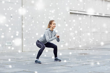 Image showing happy woman doing squats and exercising outdoors