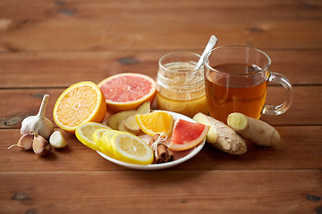 Image showing ginger tea with honey, citrus and garlic on wood