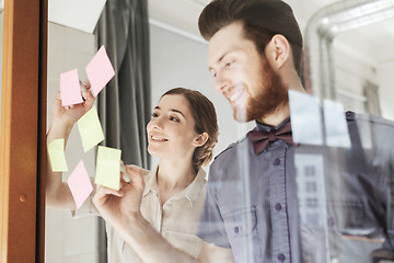 Image showing happy creative team writing on stickers at office