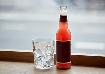 Image showing bottle of lemonade and glass with ice on table