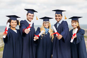 Image showing happy students in mortar boards with diplomas