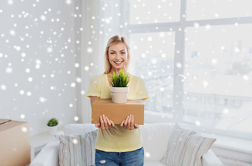 Image showing smiling young woman with box and plant at home