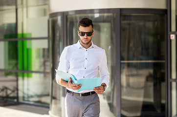 Image showing young man with business file on city street