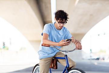 Image showing man with smartphone and earphones on bicycle