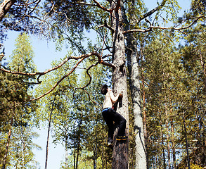 Image showing young brunette man climbing on tree with rope, lifestyle people 