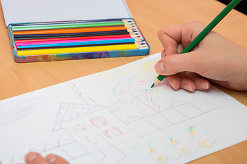 Image showing The girl draws a picture with colored pencils on paper, close-up