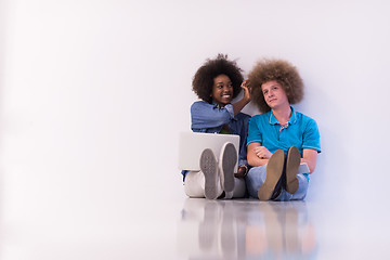 Image showing multiethnic couple sitting on the floor with a laptop and tablet