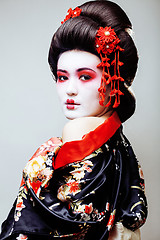 Image showing young pretty geisha in black kimono among sakura, asian ethno