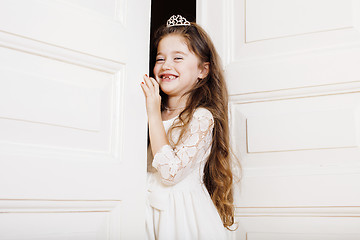 Image showing little cute girl at home, opening door well-dressed in white dress, adorable milk fairy teeth