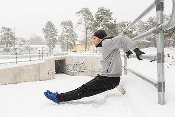 Image showing sports man doing triceps dips at fence in winter