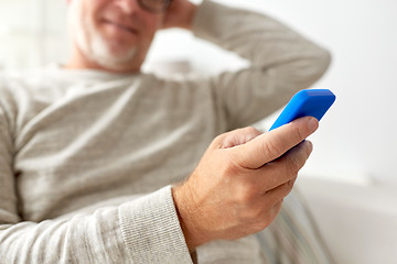 Image showing close up of old man texting on smartphone at home