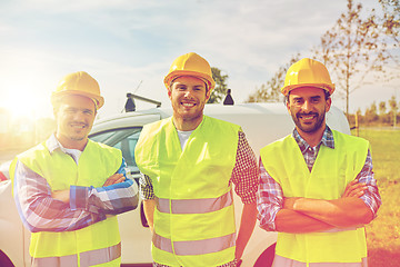 Image showing happy male builders in high visible vests outdoors