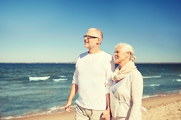 Image showing happy senior couple walking along summer beach