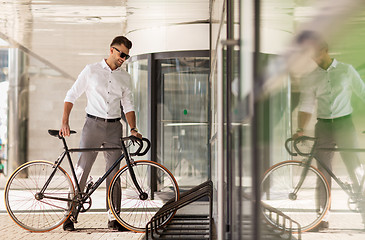 Image showing young man parking his bicycle on city street