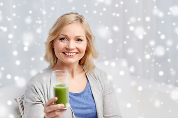 Image showing happy woman drinking green juice or shake at home