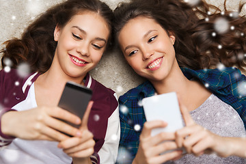 Image showing happy teenage girls lying on floor with smartphone