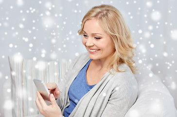 Image showing smiling woman with smartphone texting at home