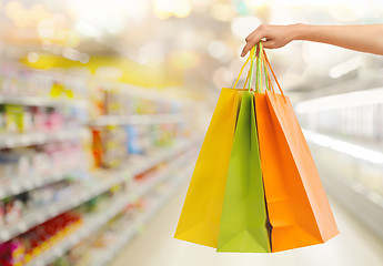 Image showing hand with shopping bags over supermarket