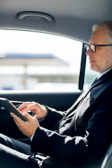 Image showing senior businessman with tablet pc driving in car