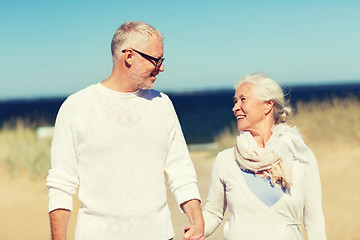 Image showing happy senior couple holding hands on summer beach