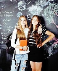 Image showing back to school after summer vacations, two teen real girls in classroom with blackboard painted together