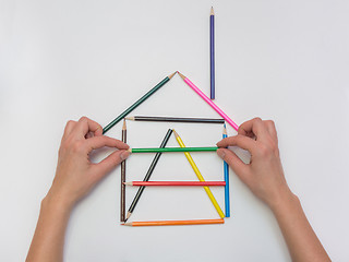 Image showing Female hands gently put a pencil next to the house layout, close-up