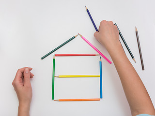 Image showing Women\'s hands are building a wooden house from pencils