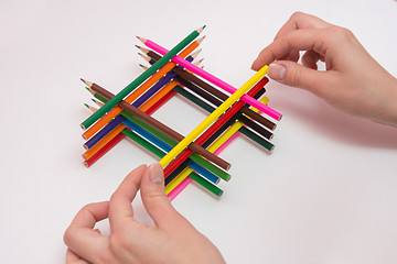 Image showing She builds a well of pencils, white background, close-up