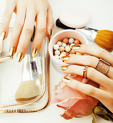 Image showing woman hands with golden manicure and many rings holding brushes,