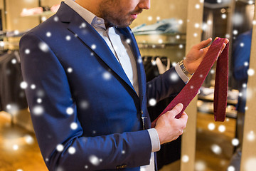 Image showing close up of man trying tie on at clothing store