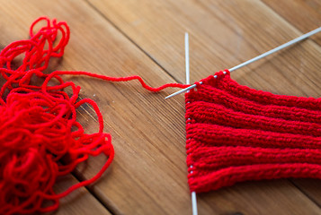 Image showing hand-knitted item with knitting needles on wood