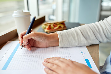 Image showing woman with paper form having lunch at cafe