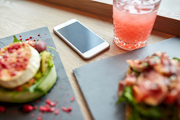 Image showing smartphone, glass of drink and food on cafe table