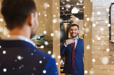 Image showing man trying tie on at mirror in clothing store