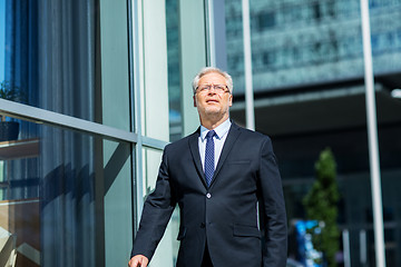 Image showing senior businessman walking along city street