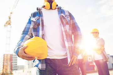 Image showing close up of builder holding hardhat at building