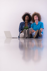 Image showing multiethnic couple sitting on the floor with a laptop and tablet