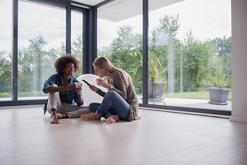 Image showing multiethnic women sit on the floor and drinking coffee