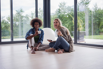 Image showing multiethnic women sit on the floor and drinking coffee