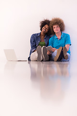 Image showing multiethnic couple sitting on the floor with a laptop and tablet