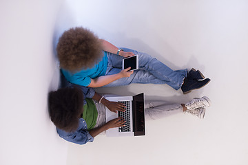 Image showing multiethnic couple sitting on the floor with a laptop and tablet