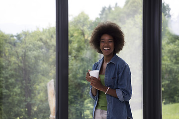 Image showing African American woman drinking coffee looking out the window