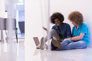 Image showing multiethnic couple sitting on the floor with a laptop and tablet