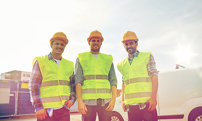 Image showing happy male builders in high visible vests outdoors