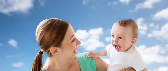 Image showing happy young mother with little baby over blue sky