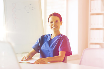 Image showing happy female doctor or nurse writing to clipboard