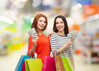 Image showing smiling teenage girls with shopping bags and money