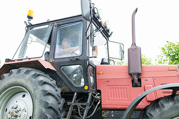 Image showing senior man driving tractor at farm