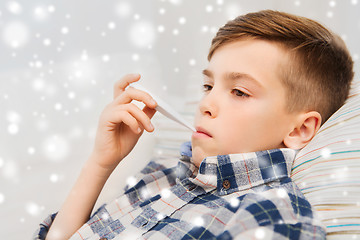 Image showing ill boy with flu and thermometer at home