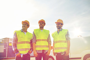 Image showing happy male builders in high visible vests outdoors